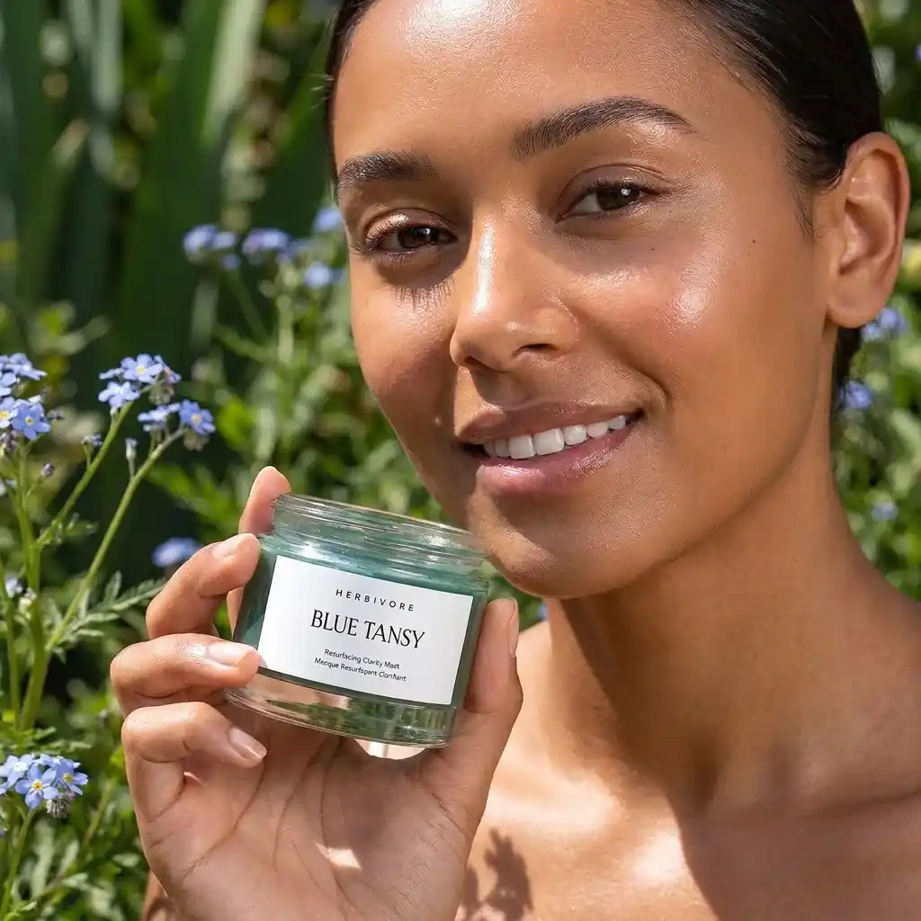 Woman holding a jar of Herbivore Blue Tansy Resurfacing Mask outdoors