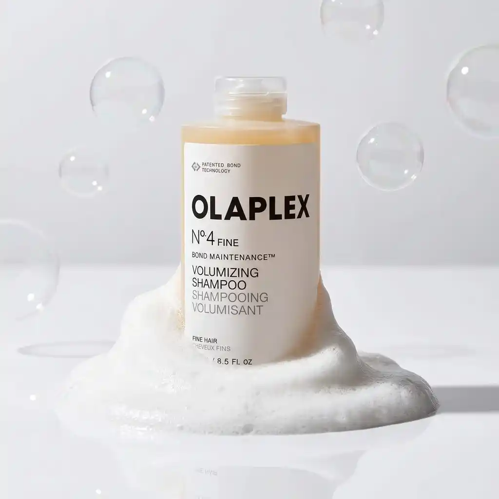 Cream Olaplex No. 4 Fine volumizing shampoo bottle on a mound of white foam with floating bubbles